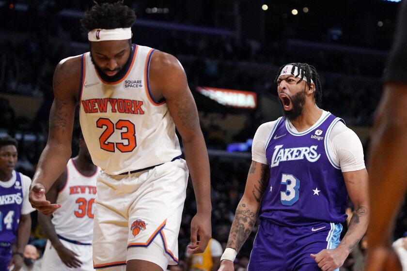 Lakers forward Anthony Davis, right, is pumped up after dunking on the Knicks' Mitchell Robinson (23). 