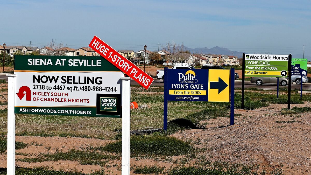 Signs advertising new housing developments are posted in Gilbert, Ariz. Residents of L.A. and Orange counties are increasingly moving to cheaper areas, including Arizona.