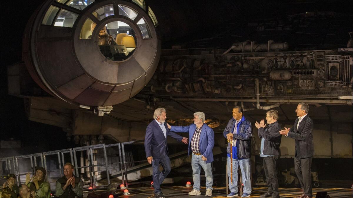 Chewbacca watches from the driver's seat of the Millennium Falcon as Harrison Ford, left, is greeted by "Star Wars" creator George Lucas, Billy Dee Williams, Mark Hamill and Walt Disney Company CEO Bob Iger at the unveiling of Star Wars: Galaxy's Edge.