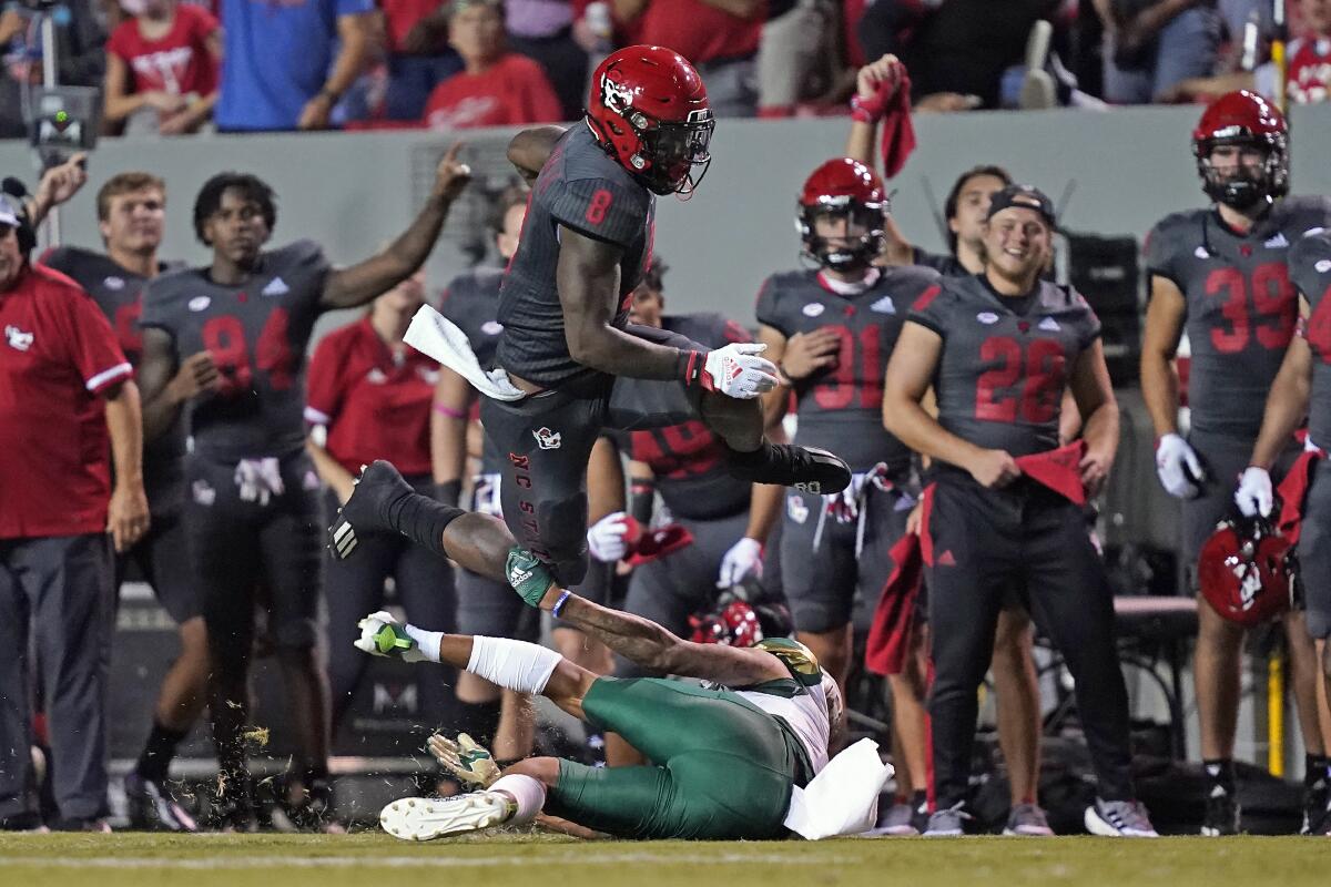North Carolina State running back Ricky Person Jr. (8) jumps over South Florida safety Matthew Hill during the first half of an NCAA college football game in Raleigh, N.C., Thursday, Sept. 2, 2021. (AP Photo/Gerry Broome)