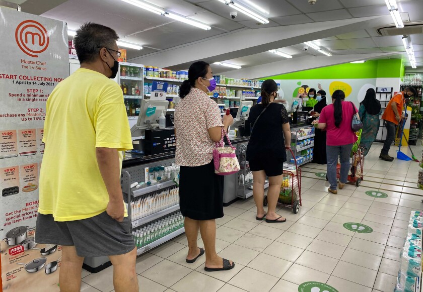 People wear masks and observe social distancing while lining up to pay at a supermarket in Singapore, Friday, May 14, 2021. Singapore further tightened its COVID-19 measures as it sought to control an increase in untraceable coronavirus infections in the city-state. (AP Photo/Zen Soo