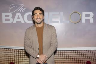 'The Bachelor' star Joey Graziadei smiles in front of a Bachelor TV show poster