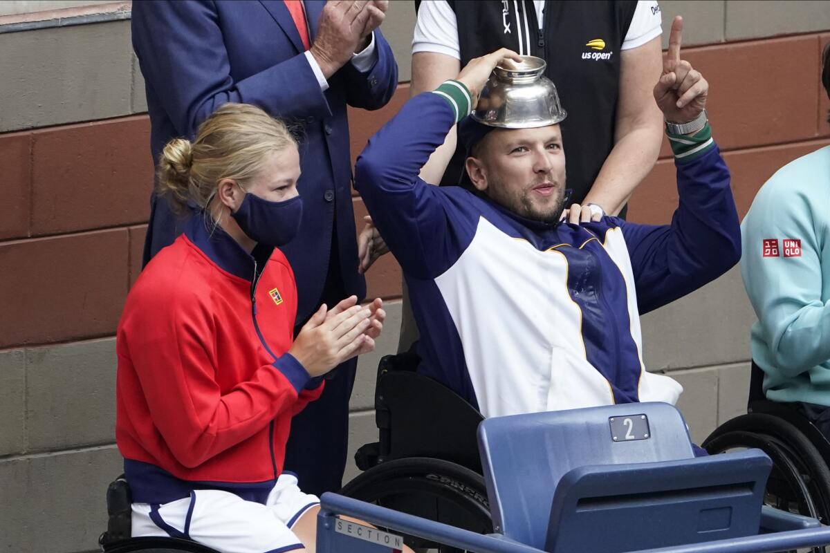 Diede De Groot, of the Netherlands, left, and Dylan Alcott, of Australia react to the crowd while watching play between Novak Djokovic, of Serbia, and Daniil Medvedev, of Russia, during the men's singles final of the US Open tennis championships, Sunday, Sept. 12, 2021, in New York. (AP Photo/Seth Wenig)