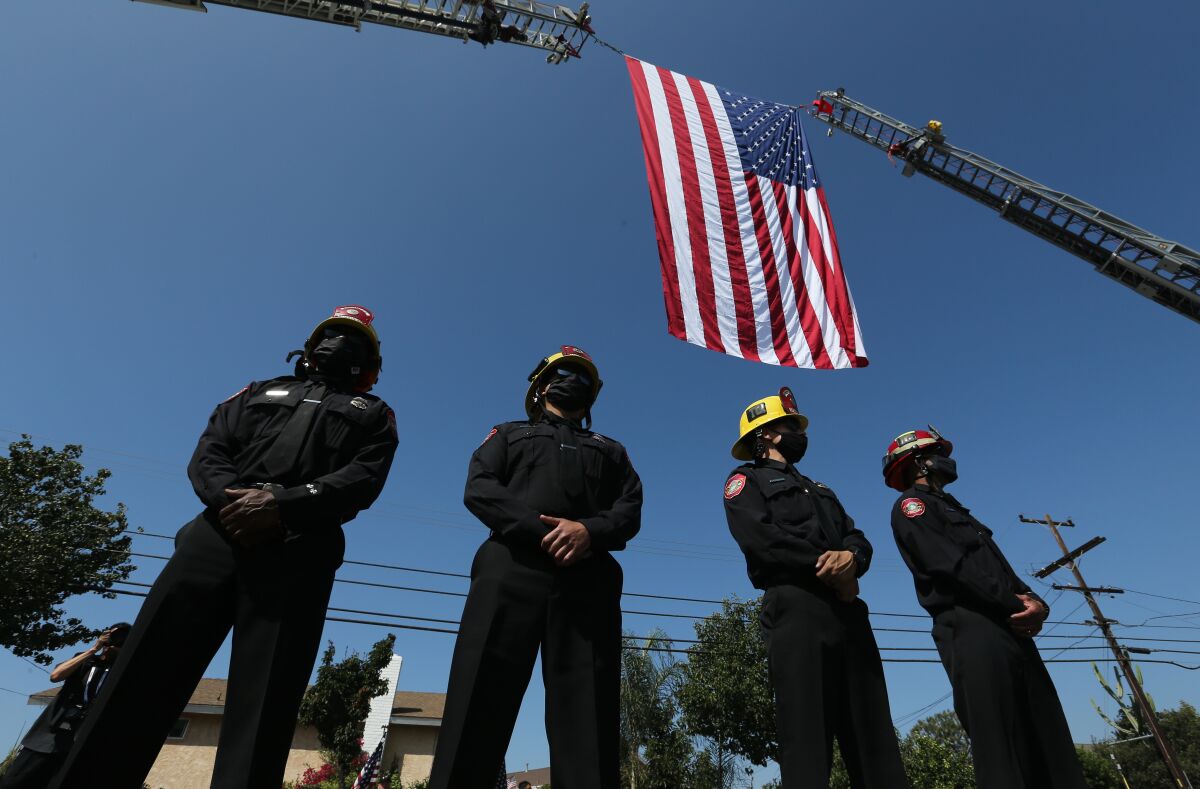 Anaheim Fire Department firefighters line up under a flag arch as motorcade carrying Charles Morton's body passes Tuesday.