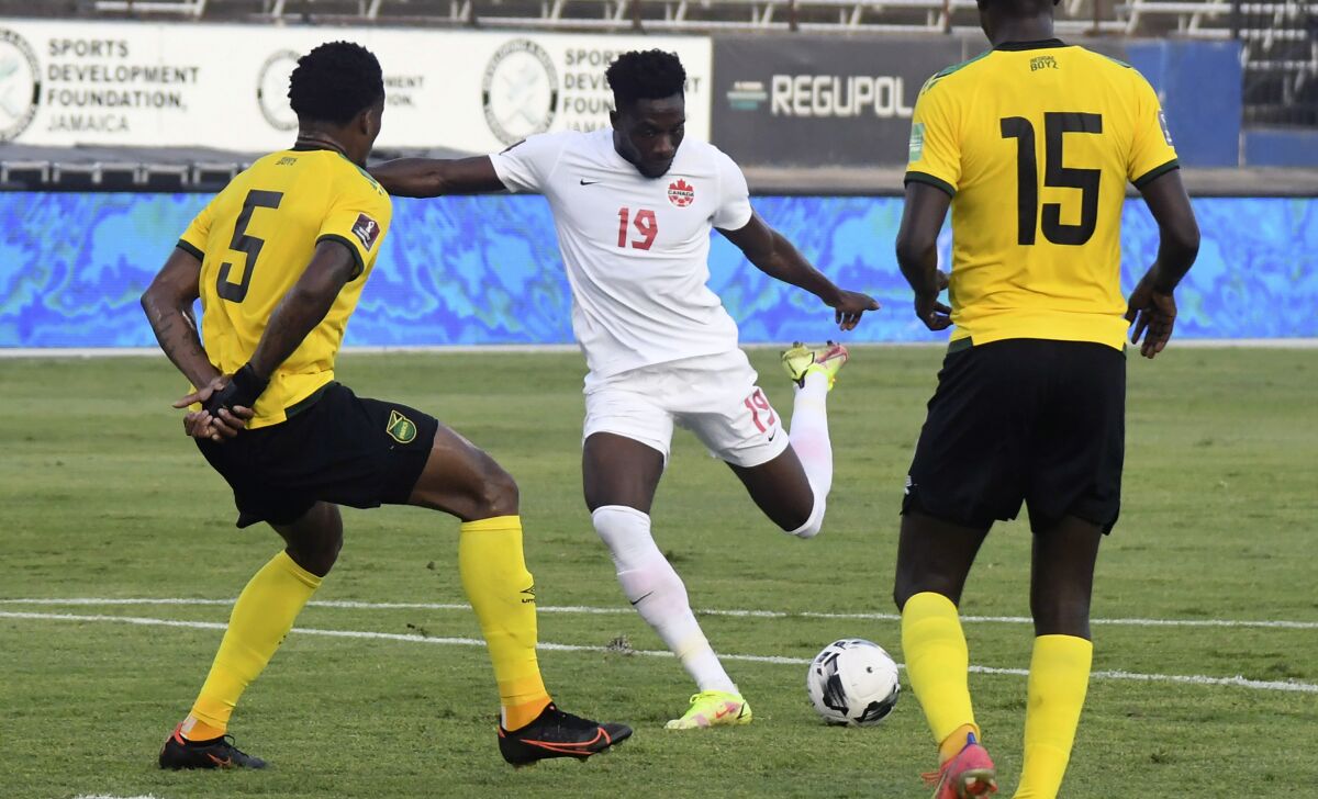 Canada's Alphonso Davies fights for the ball against Jamaica's Alvas Powell and Je-vaughn Watson 