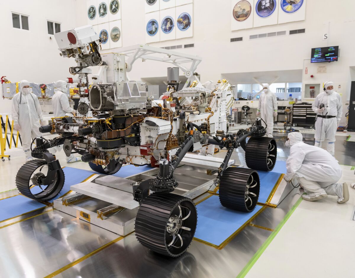FILE - In this Dec. 17, 2019, file photo made available by NASA, engineers watch the first driving test for the Mars 2020 rover Perseverance. in a clean room at the Jet Propulsion Laboratory in Pasadena, Calif. NASA has delayed the launch of its newest Mars rover yet again because of rocket issues. The space agency has until mid-August to send the Perseverance rover to the red planet to look for signs of ancient microscopic life, before having to wait until 2022. Managers are now targeting no earlier than July 30 for a liftoff from Cape Canaveral, Florida, eating up half of the month-long launch window. (J. Krohn/NASA via AP, File)
