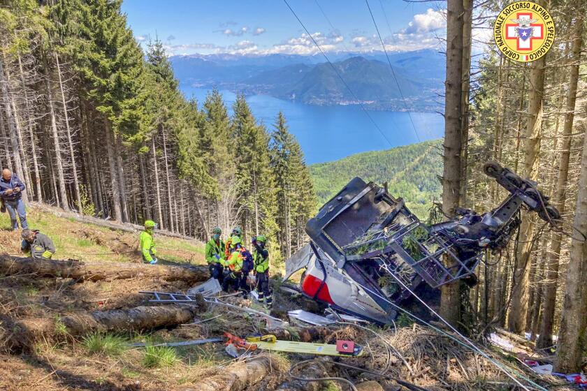 Rescuers work by the wreckage of a cable car after it collapsed near the summit of the Stresa-Mottarone line in the Piedmont region, northern Italy, Sunday, May 23, 2022. A mountaintop cable car plunged to the ground in northern Italy on Sunday, killing at least nine people and sending at least three more to the hospital, authorities said. (Soccorso Alpino e Speleologico Piemontese via AP)