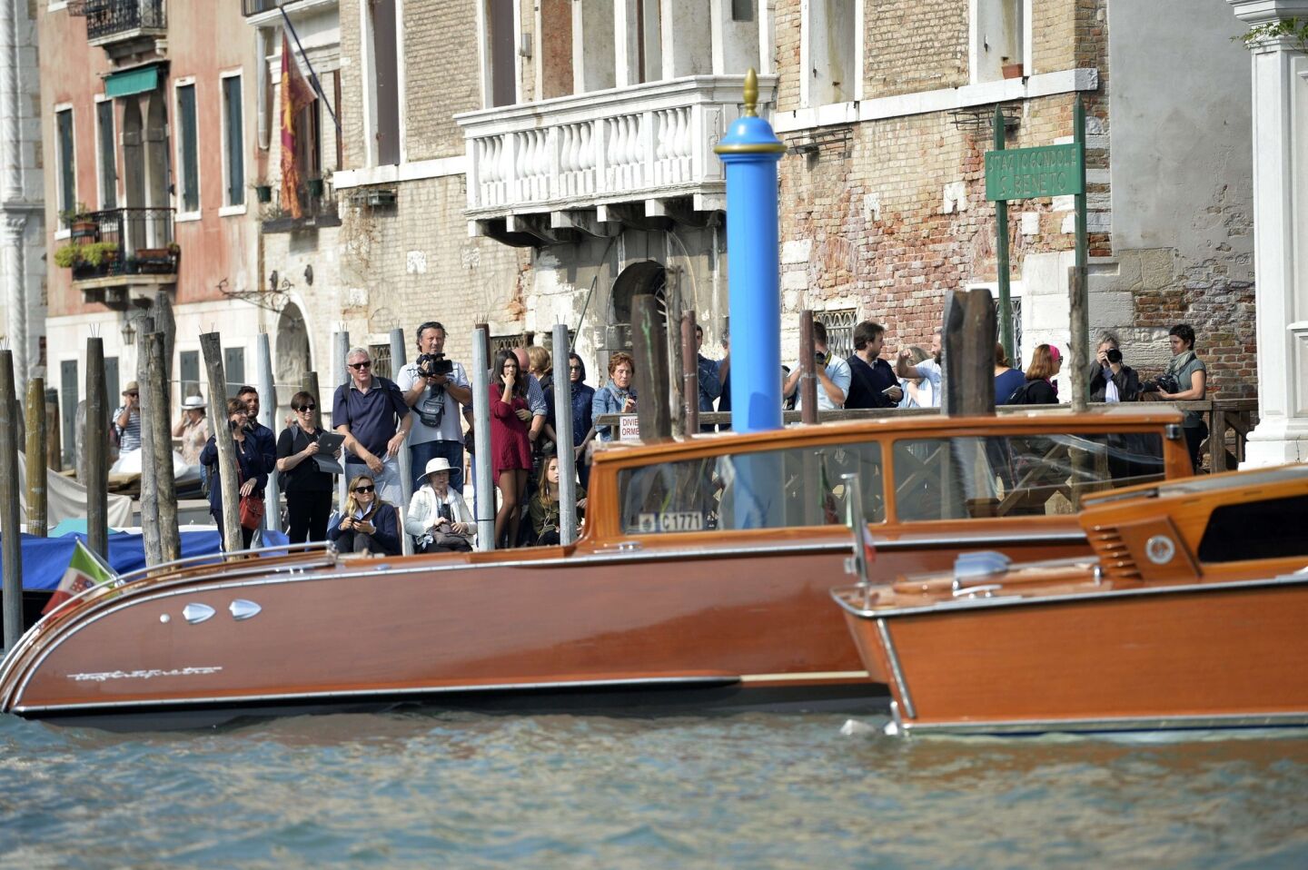 People and photographers wait near the Aman Canal Grande hotel, where London lawyer Amal Alamuddin was staying before her Saturday wedding to George Clooney.