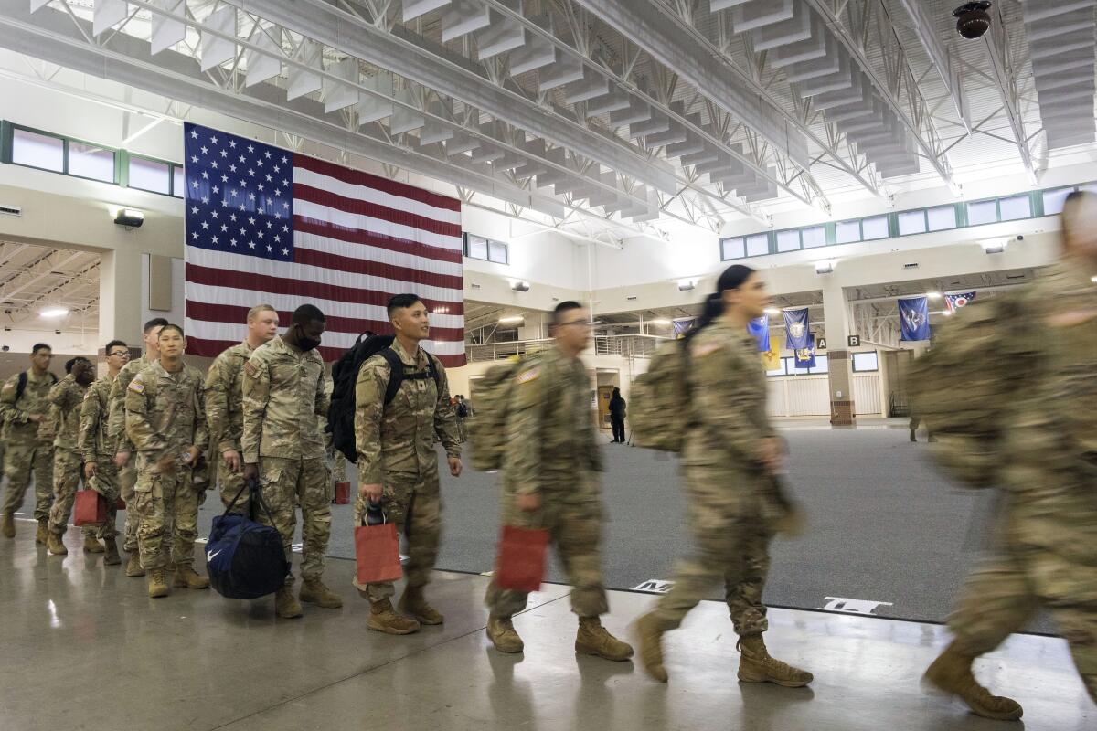 FILE - About 130 soldiers with the U.S. Army's 87th Division Sustainment Support Battalion, 3rd Division Sustainment Brigade, wait to board a chartered plane during their deployment to Europe, March 11, 2022, at Hunter Army Airfield in Savannah, Ga. The Army is significantly cutting the total number of soldiers it expects to have in the force over the next two years, as the U.S. military faces what a top general called “unprecedented challenges” in bringing in new recruits. (AP Photo/Stephen B. Morton, File)