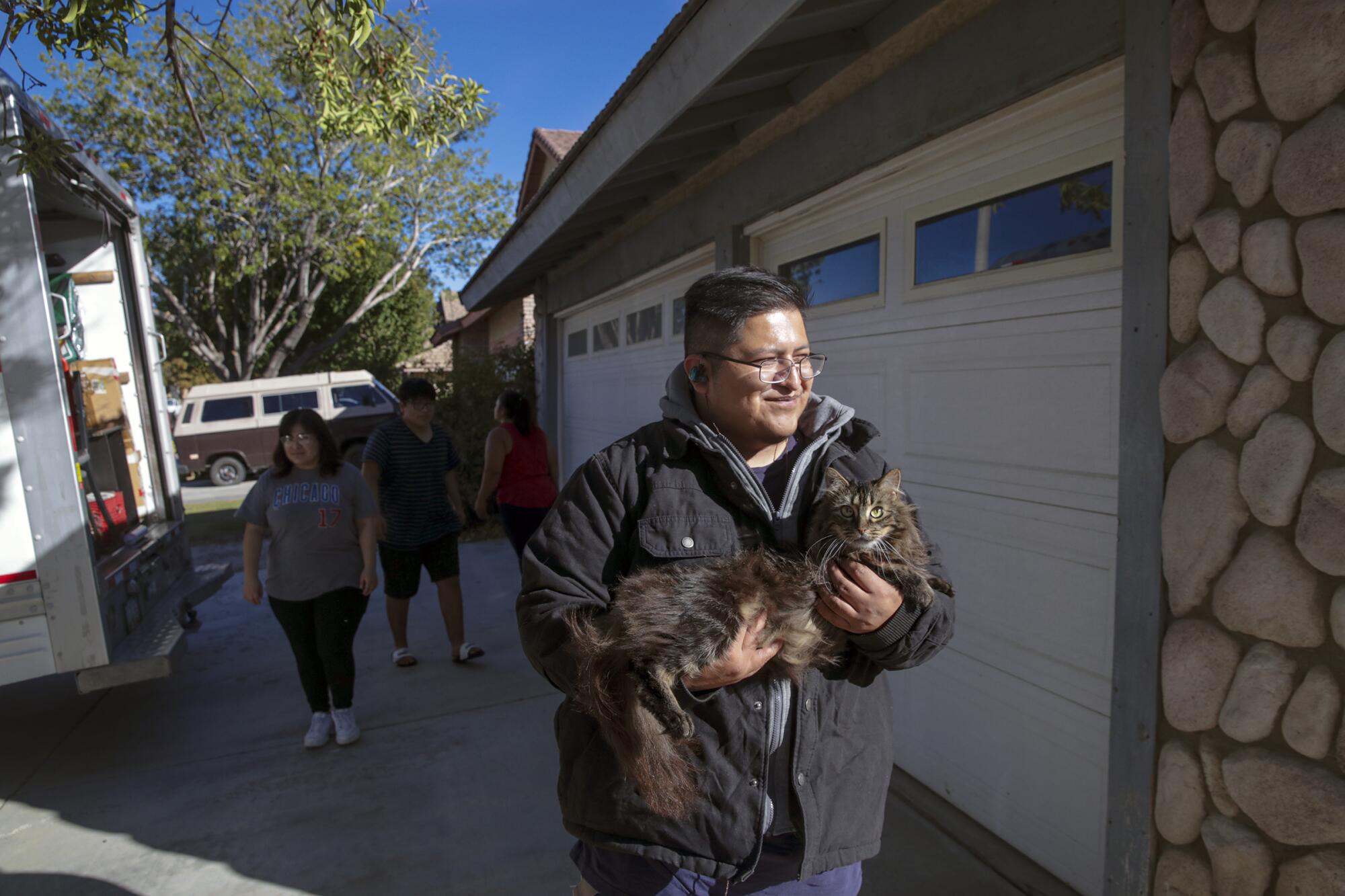 Jafet Martinez Oceguera carries his pet cat into the family's new home in Lancaster.