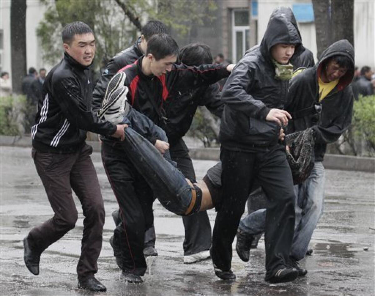 Kyrgyz protesters carry a wounded colleague during clashes with riot police in Bishkek, Kyrgyzstan, Wednesday, April 7, 2010. Police in Kyrgyzstan opened fire on thousands of angry protesters who tried to seize the main government building amid rioting in the capital as protests spread across the Central Asian nation. (AP Photo/Ivan Sekretarev)