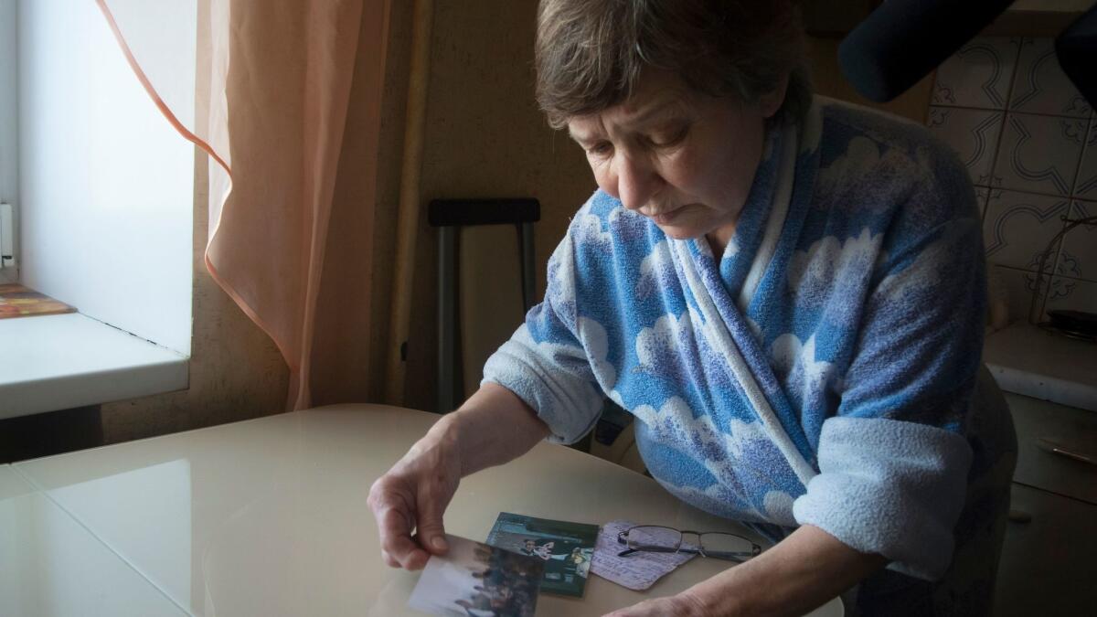 Farkhanur Gavrilova looks at photos of her son, Ruslan Gavrilov, in the village of Kedrovoye, Russia. He was one of seven men in the village who are believed to have joined a private military company called Wagner.