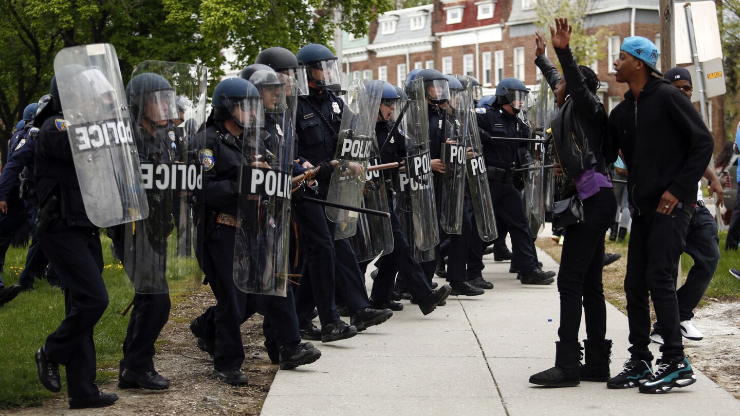 Baltimore police officers in riot gear push protesters back near Mondawmin Mall.