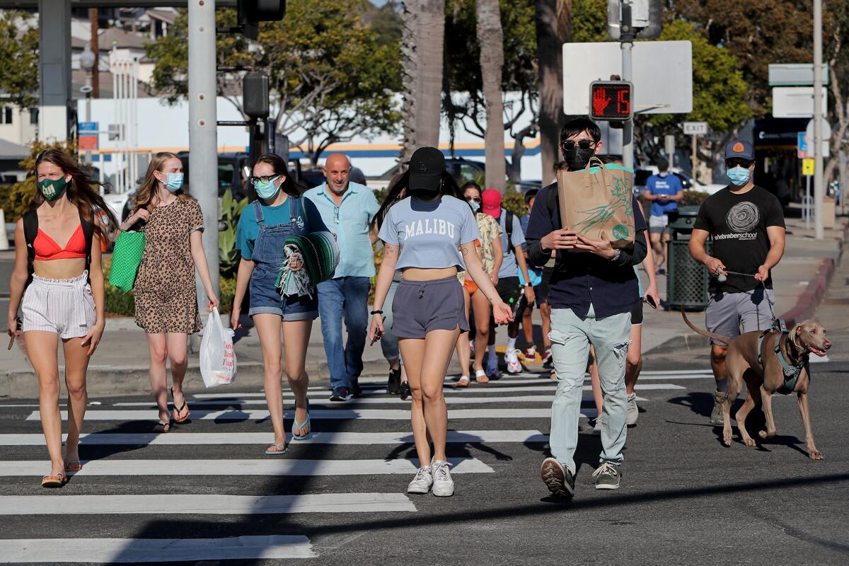 A crowd of people cross South Coast Highway toward Laguna Main Beach on Saturday.