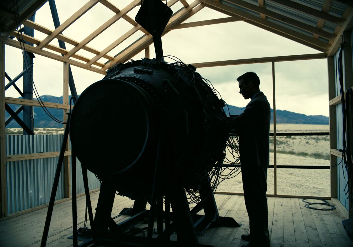 A figure in silhouette stands next to the atomic bomb