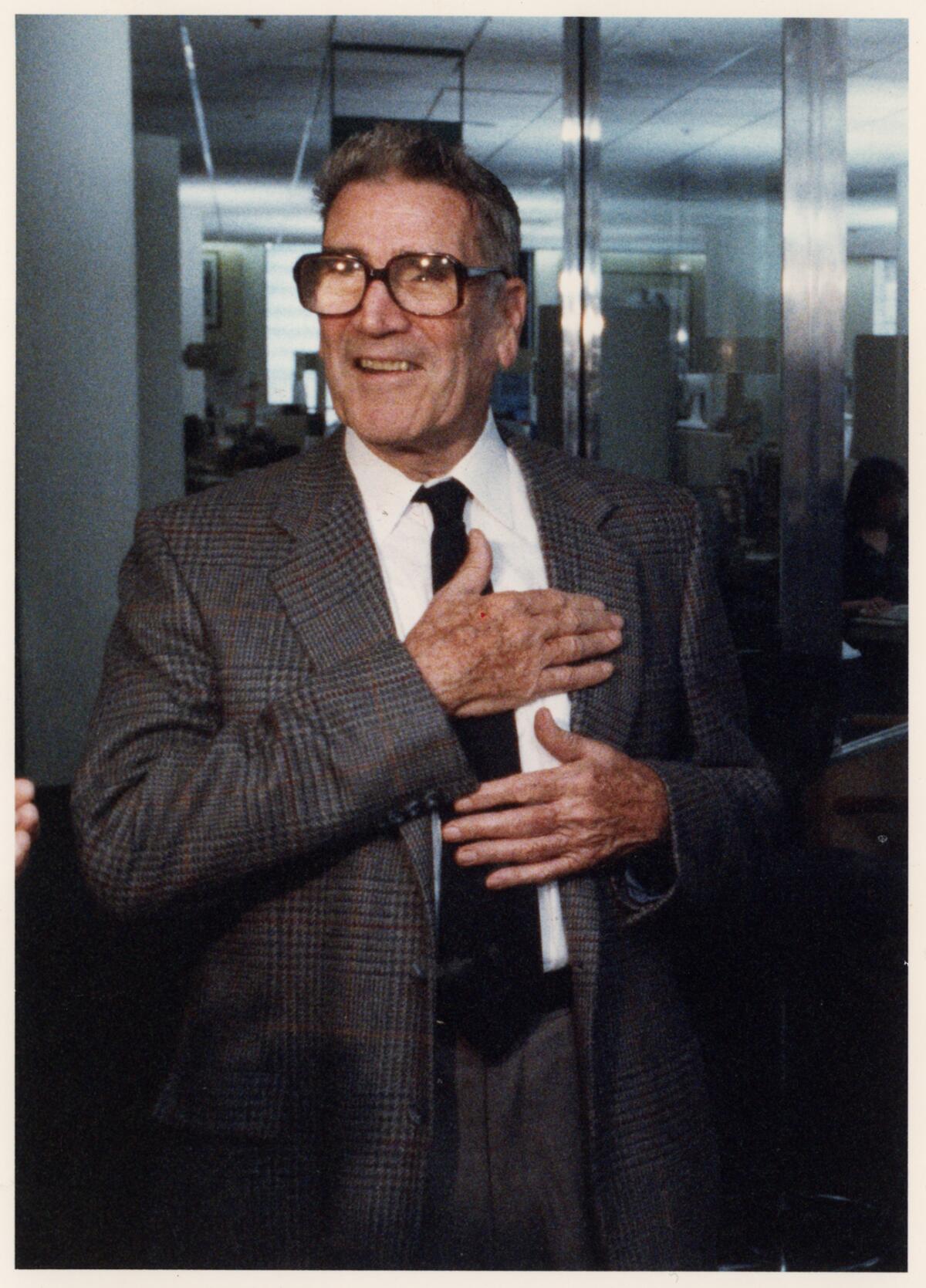 Jim Murray wearing a jacket and tie and signature thick-framed glasses.
