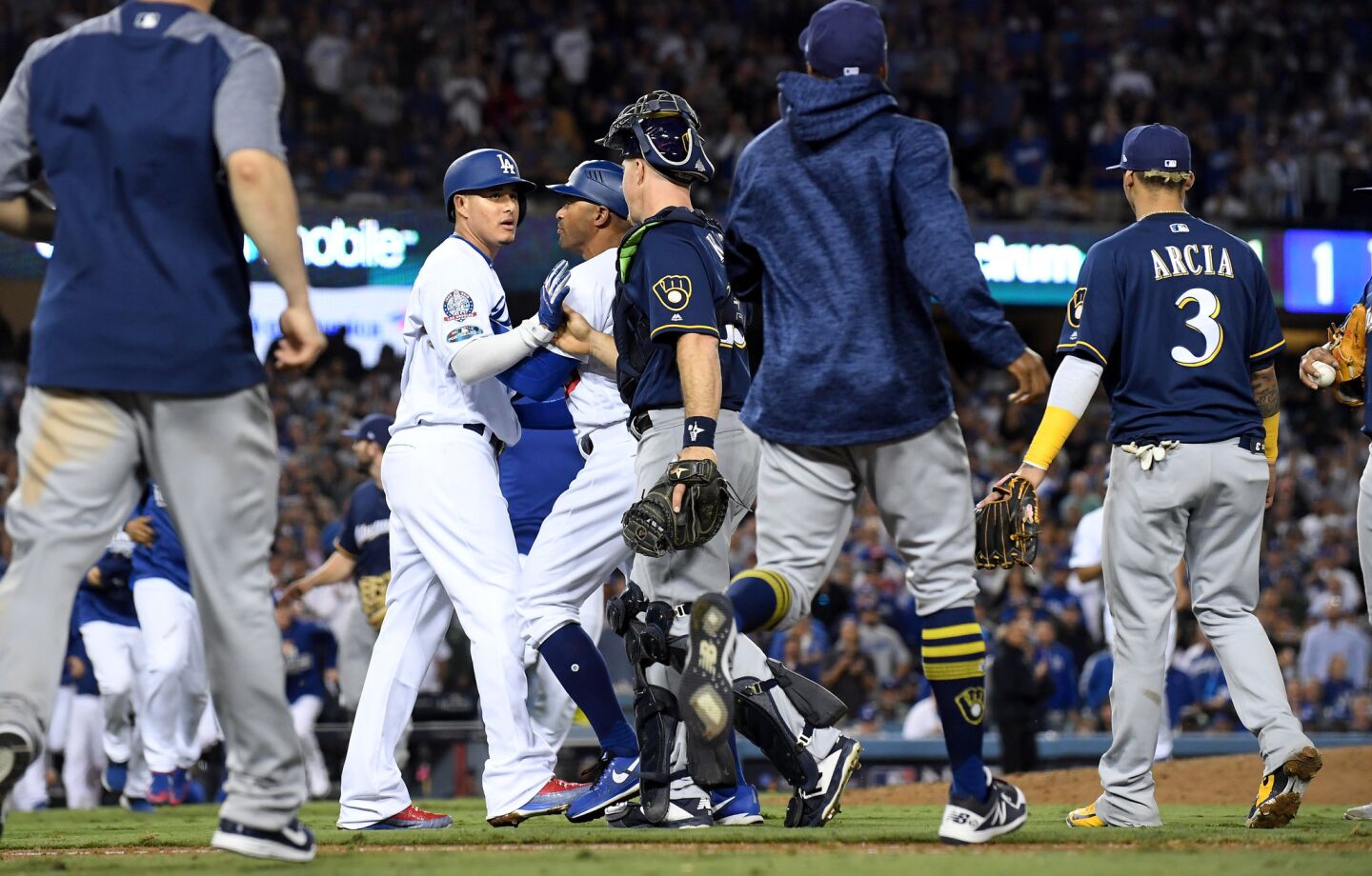 Dodgers Manny Machado has to be held back by 1st base coach George Lombard after an argument with Brewers 1st baseman Jesus Aguilar.