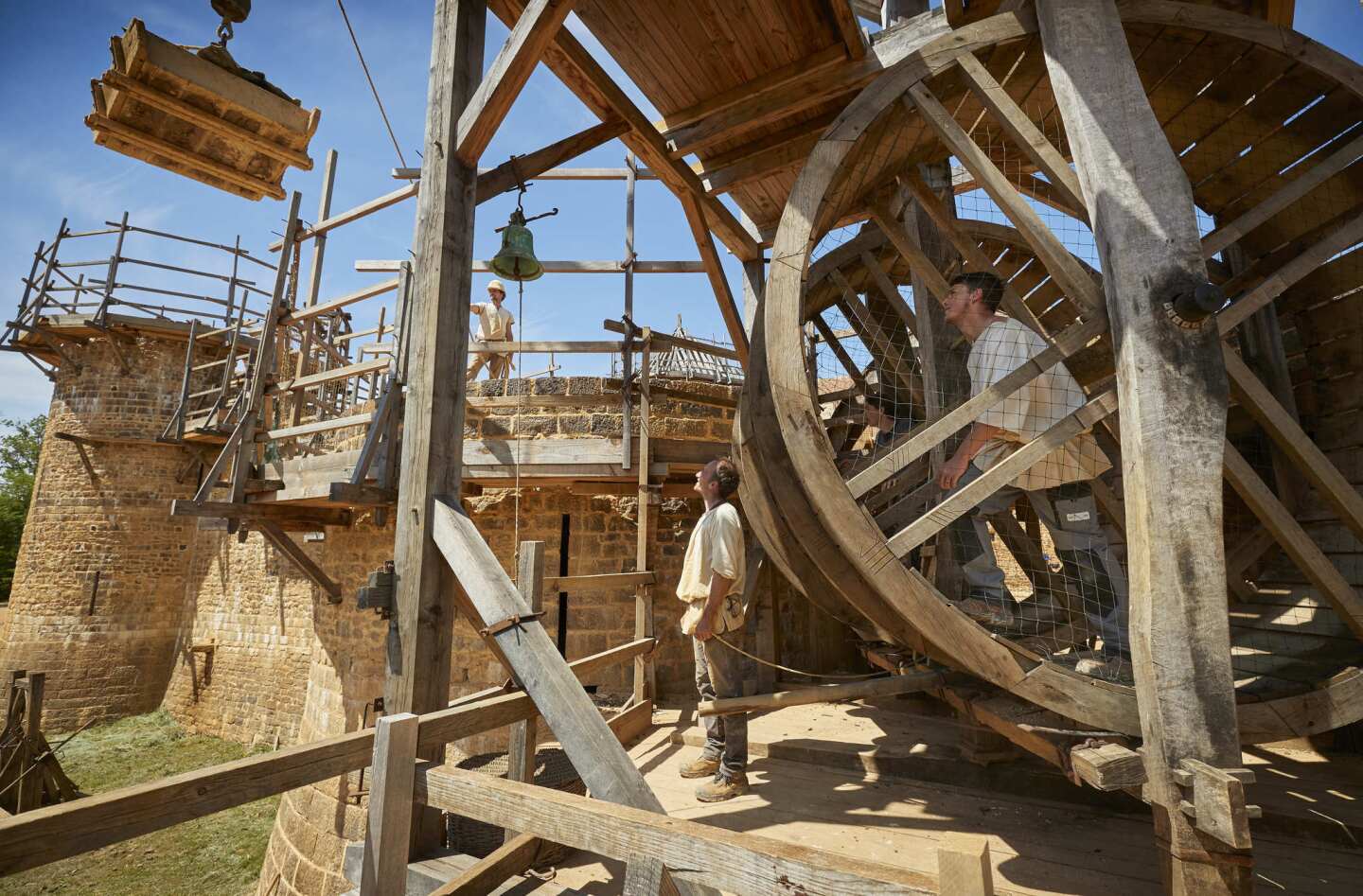 Masons drive the treadwheel crane at Guedelon medieval castle project, a back-to-the-future project re-creating a 13th century castle from scratch in the heart of Burgundy, central France.