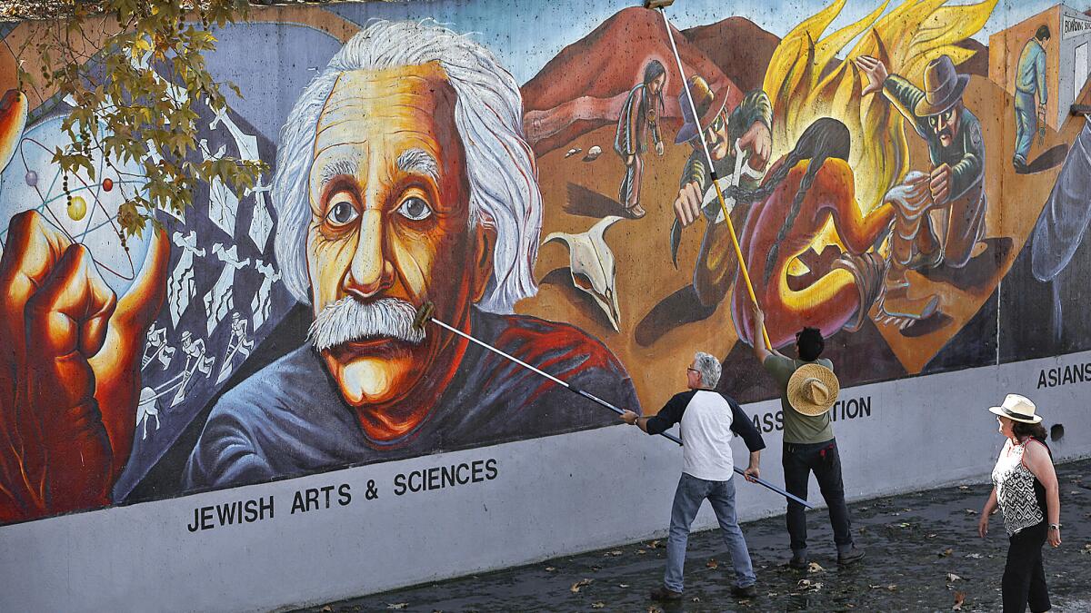 Councilman Paul Krekorian, left, helps clean the Great Wall of Los Angeles, a 2,700-foot-long mural in Valley Glen that depicts scenes from California’s history.