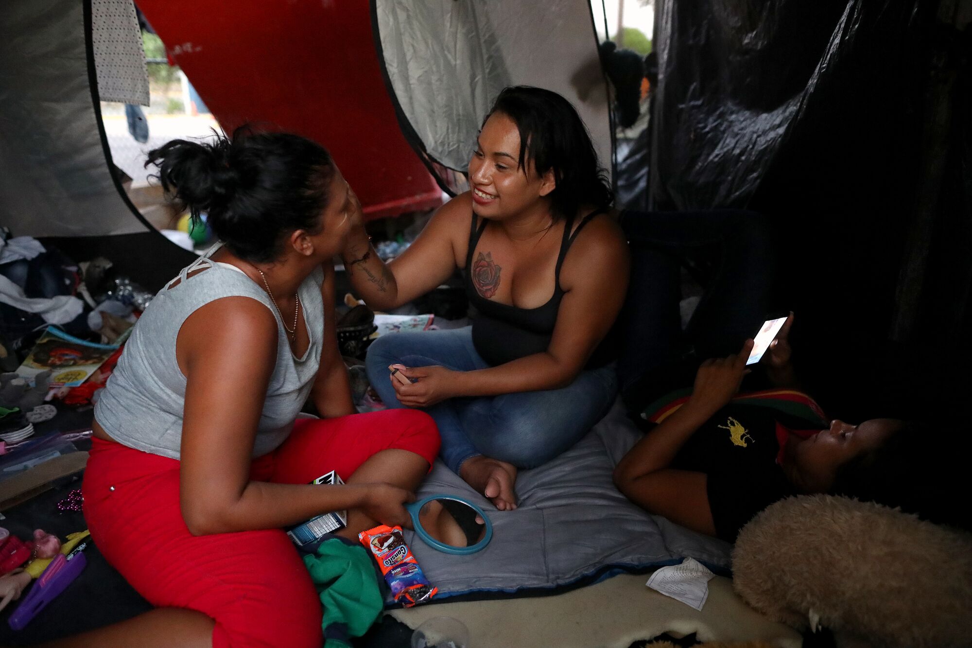 Mayela Villegas applies makeup on Johana Orellana in her tent in Matamoros, Mexico