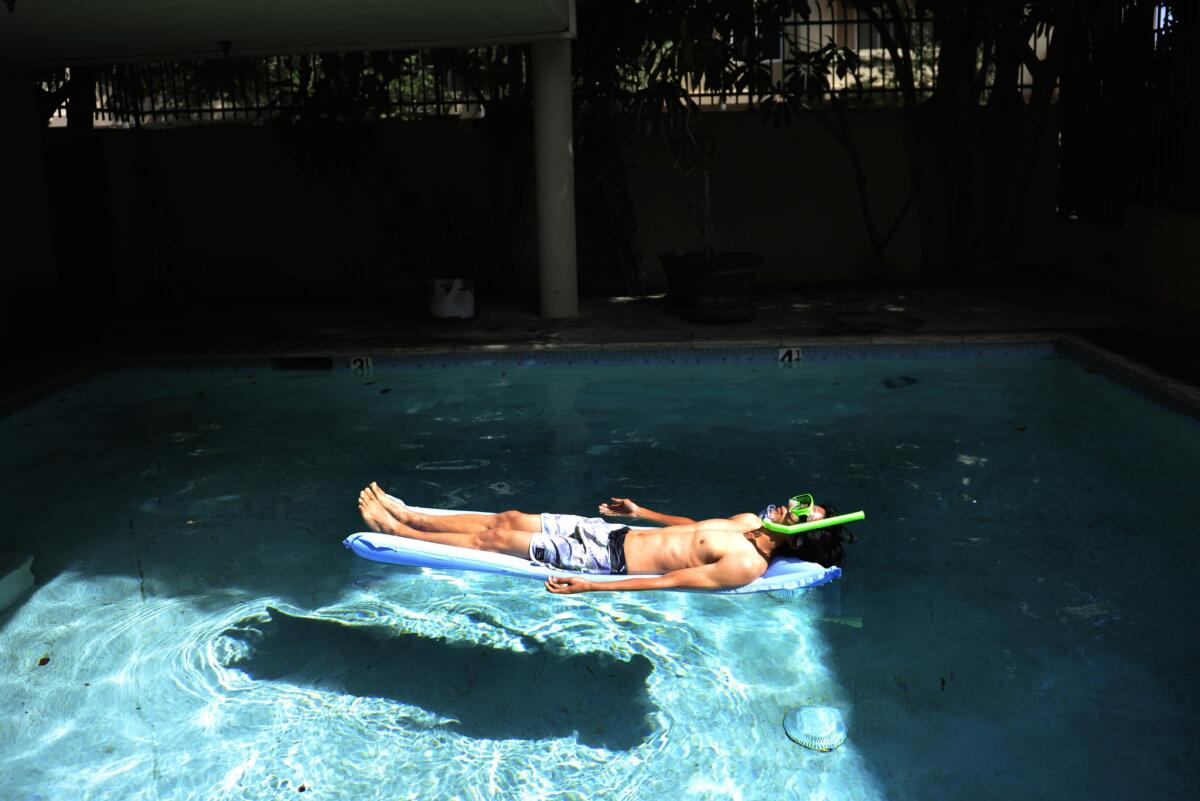 Joseph Lee, 23, a UCLA graduate from Vallejo, teamed up with research partner Benedikt Gross to produce "The Big Atlas of L.A. Pools." Here he lounges in one of the blue oases.