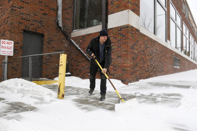 David Smith shovels the sidewalk as the first snow falls ahead of a winter storm on Tuesday, Feb. 21, 2023, in Sioux Falls, S.D. A wide swath of the Upper Midwest is bracing for a historic winter storm. The system is expected to bury parts of the region in 2 feet of snow, create dangerous blizzard conditions and bring along bitter cold temperatures. (Erin Woodiel/The Argus Leader via AP)