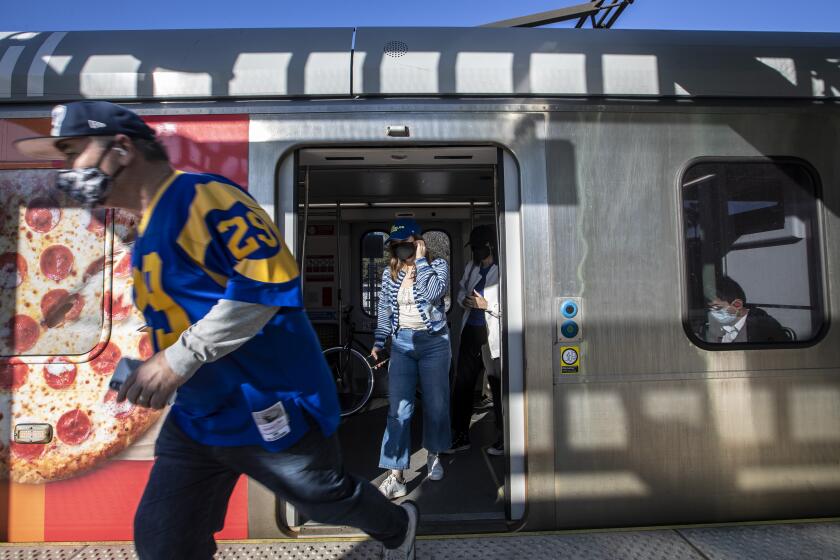 Inglewood, CA - January 30: A Rams fan runs out to catch a shuttle bus from the Metro C Line Hawthorne/Lennox station to SoFi Stadium Sunday, Jan. 30, 2022 in Inglewood, CA. (Brian van der Brug / Los Angeles Times)