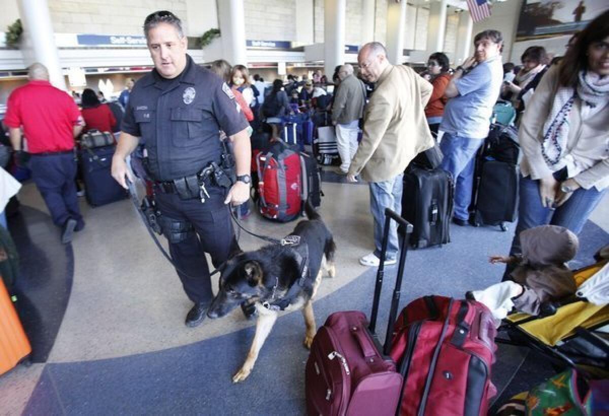 Los Angeles Airport Police officer Mike Garzon with explosives detection dog Erik monitor baggage and passengers at American Airlines Terminal 4 at LAX on Tuesday, a day after the bombing in Boston. The Transportation Security Administration says that, despite the attacks this week, it will loosen regulations on some objects that can be carried on planes, including small knives.
