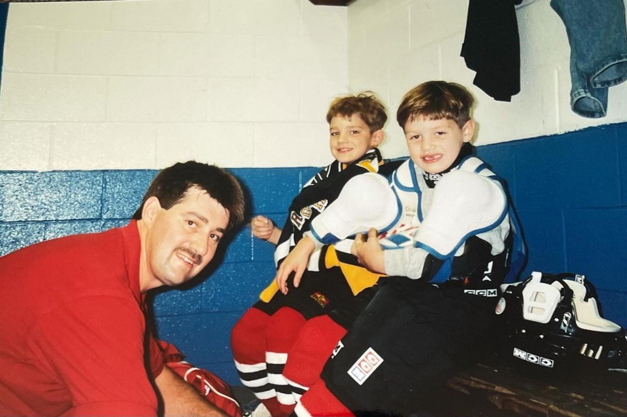 Doug Skura, left, helps two of his sons put on skates.