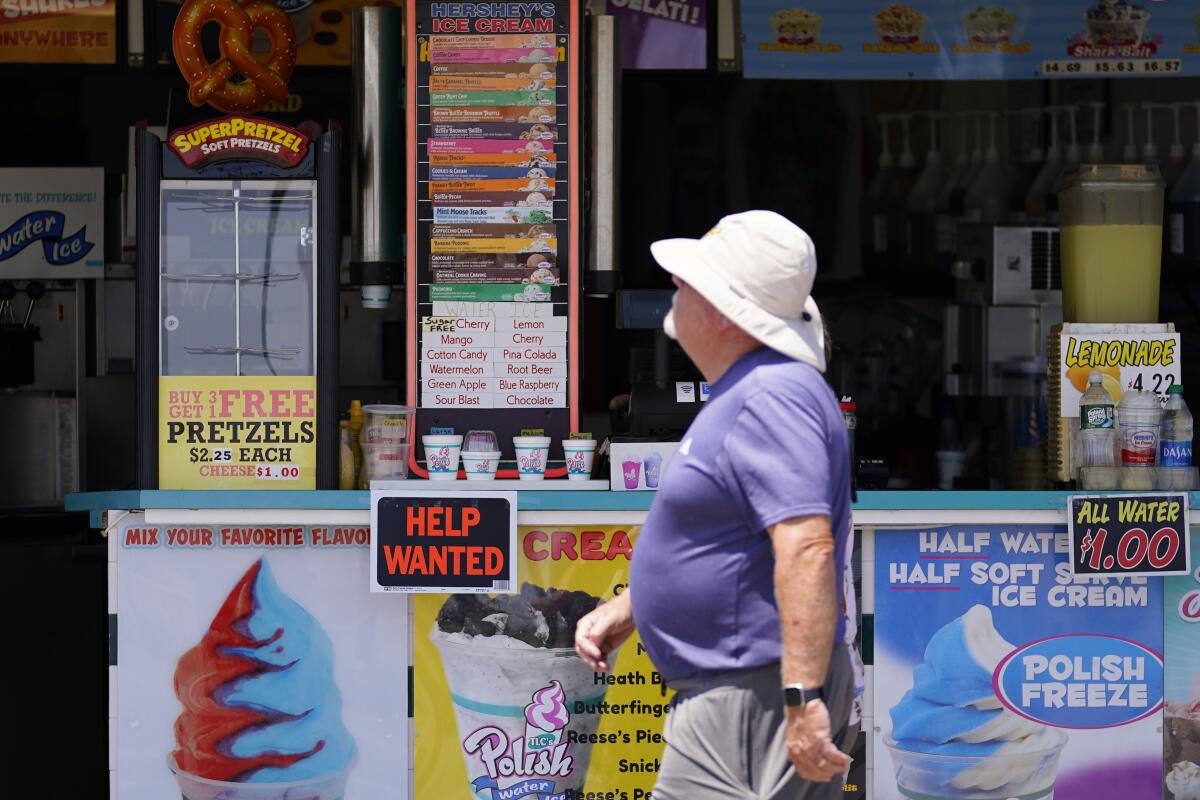 A person walks past a help wanted sign in front of a business along the boardwalk