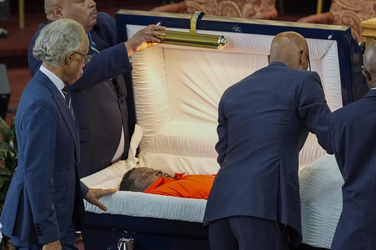 Al Sharpton and another man view a body in a coffin 