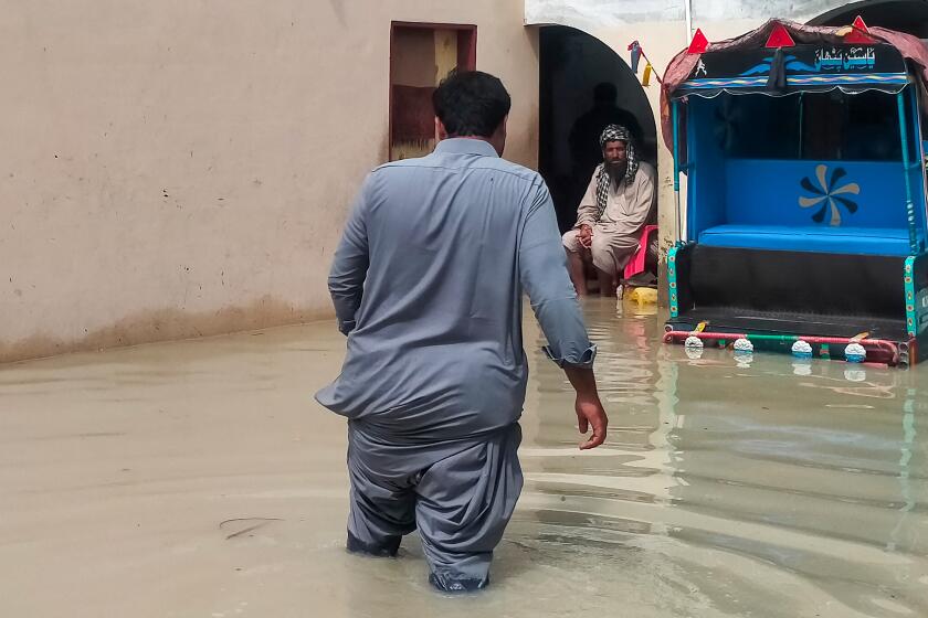 A man waves through flood waters inside a house following heavy rains in Gwadar.