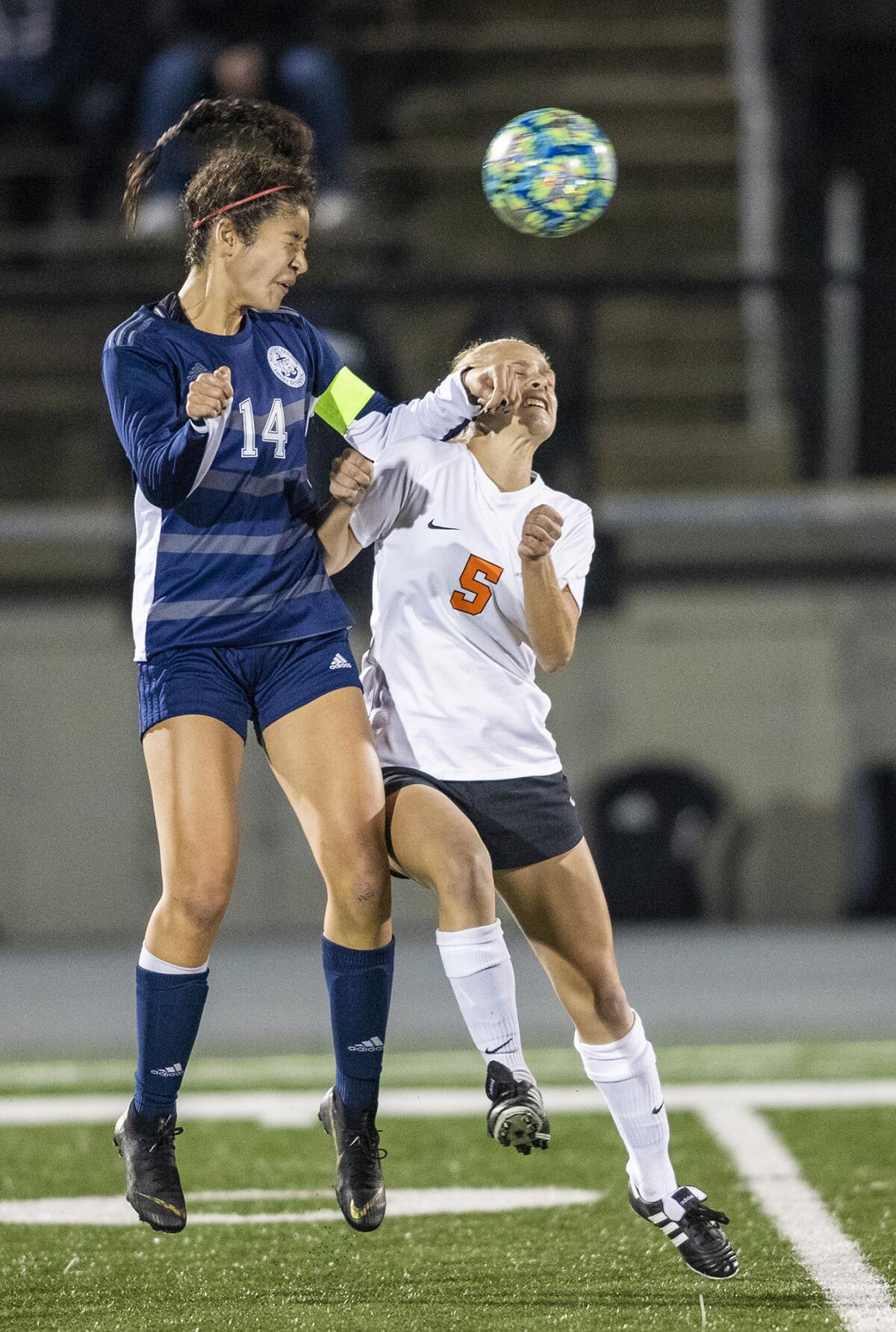 Newport Harbor's Nicole Laz, left, goes up for a header against Huntington Beach's Lexi Muche in a Sunset Conference crossover match on Thursday.