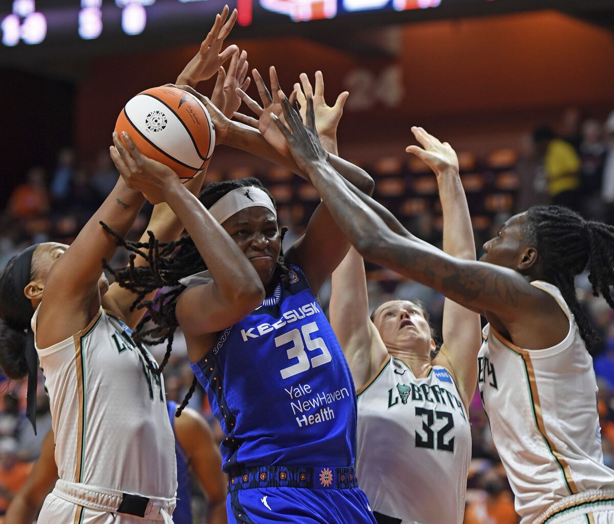 Connecticut Sun forward Jonquel Jones (35) works between New York Liberty defenders Betnijah Laney, left, Sami Whitcomb (32) and Natasha Howard during the first half of a WNBA basketball game Wednesday, Sept. 15, 2021, in Uncasville, Conn. (Sean D. Elliot/The Day via AP)