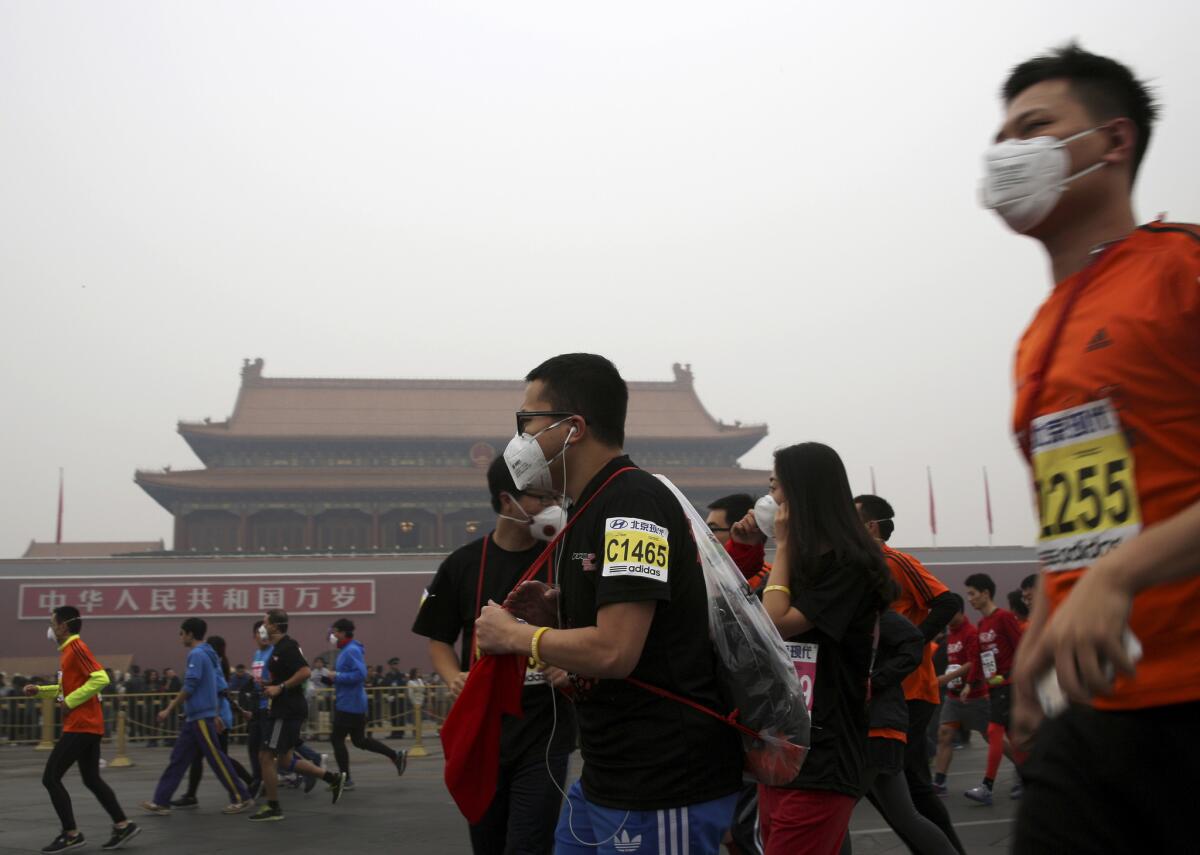 Runners moving past Tiananmen Gate wear masks to deal with smog at the Beijing International Marathon on Oct. 19.