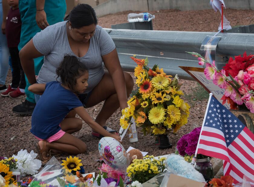 A family places flowers at a memorial outside the Cielo Vista Mall Walmart in El Paso, where 20 people were shot and killed by a gunman on Saturday. The El Paso massacre was followed on Sunday morning by a gunman's killing of nine people in Dayton, Ohio.
