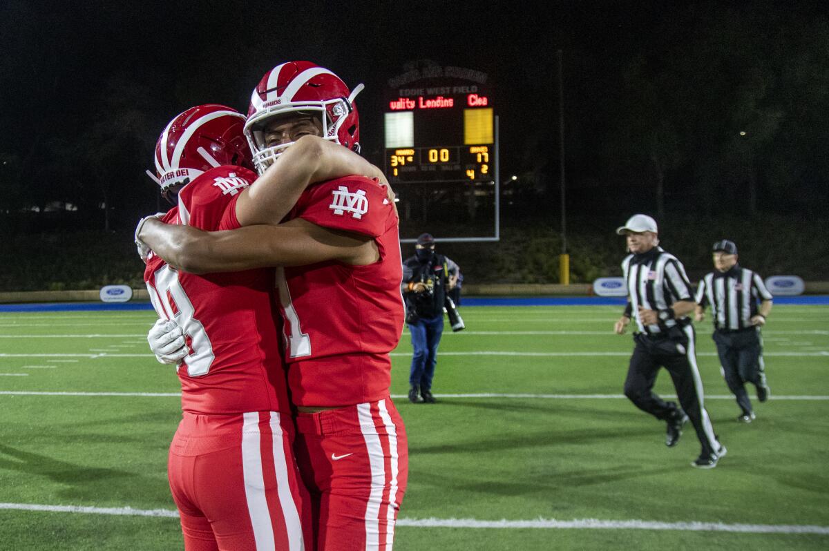 Mater Dei's Jack Ressler and Isaiah Lopez hug on the field while referees walk behind them.