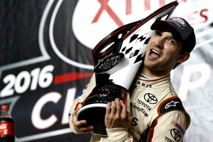 NASCAR driver Daniel Suarez celebrates with the Xfinity Series championship trophy in after winning the Ford EcoBoost 300 on Saturday.
