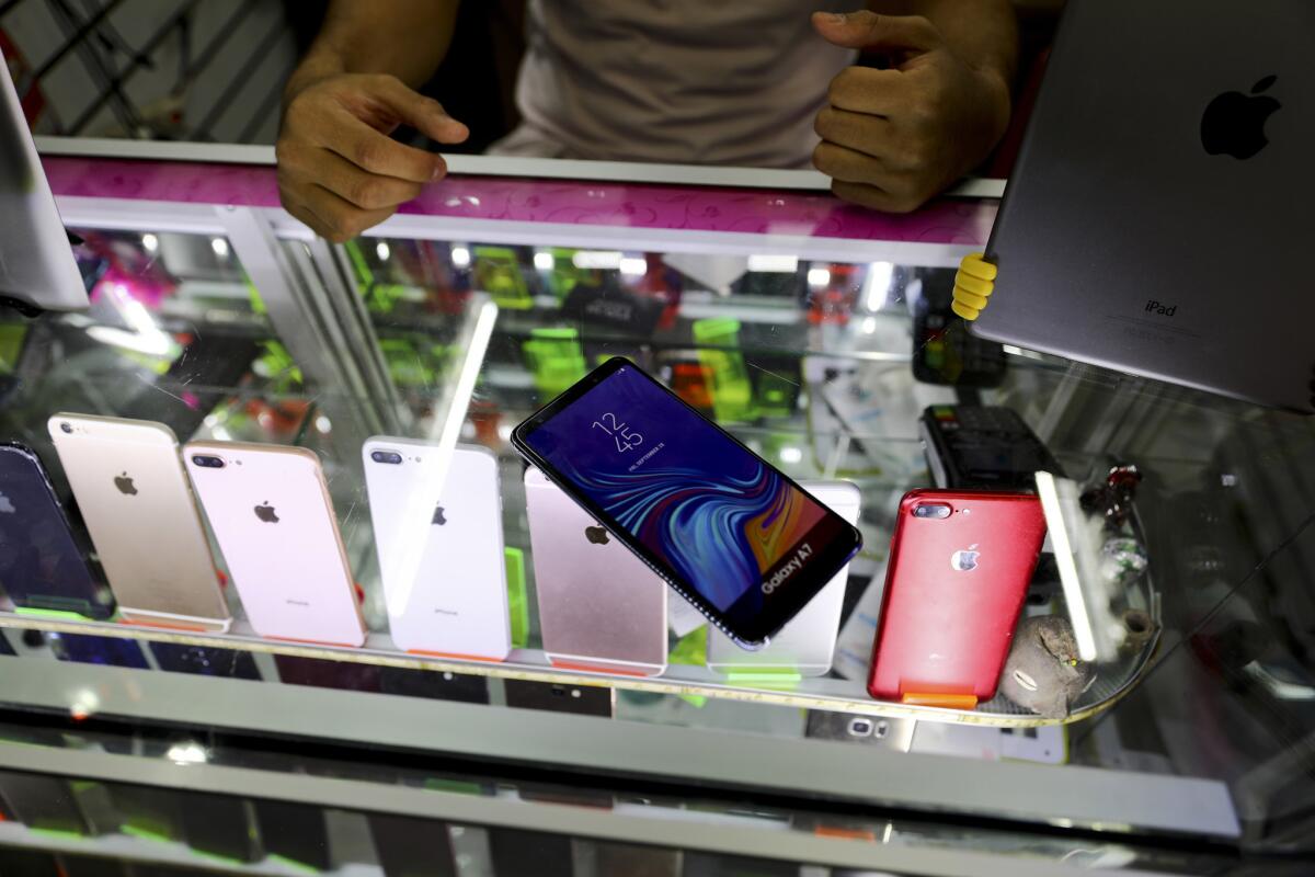Axel, un vendedor en una plaza de productos electrónicos, muestra los celulares de señuelo que la gente compra en caso de que sean asaltados y tengan que entregar sus teléfonos, en Ciudad de México.