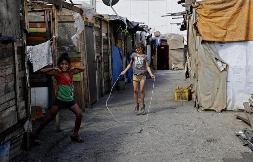 Two girls play on Jan. 28, 2019, in the old parking lot in the Caracas neighborhood of Petare where many familes moved in recent years when they couldn't afford to pay rent, and since then have lived in structures put together out of plastics, wooden planks and cardboard. EFE-EPA/Leonardo Muñoz