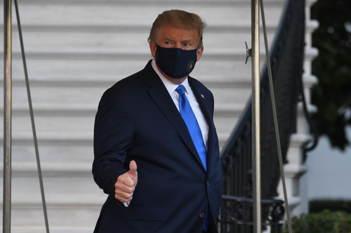 President Trump gives a thumbs-up while wearing a mask