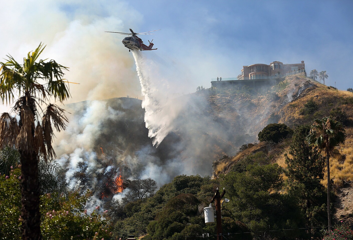 A Los Angeles Fire Department helicopter drops water on a hot spot behind houses on Hamline Place in Burbank.