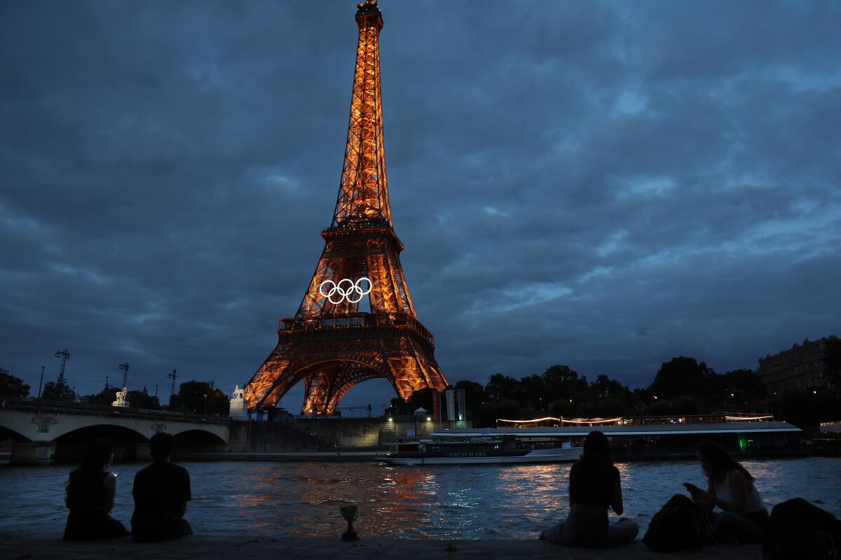 The Eiffel Tower is lit up at night days before the Olympics in Paris.