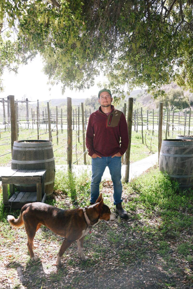 Vintner Aldo Quesada and a dog outside at his winery.