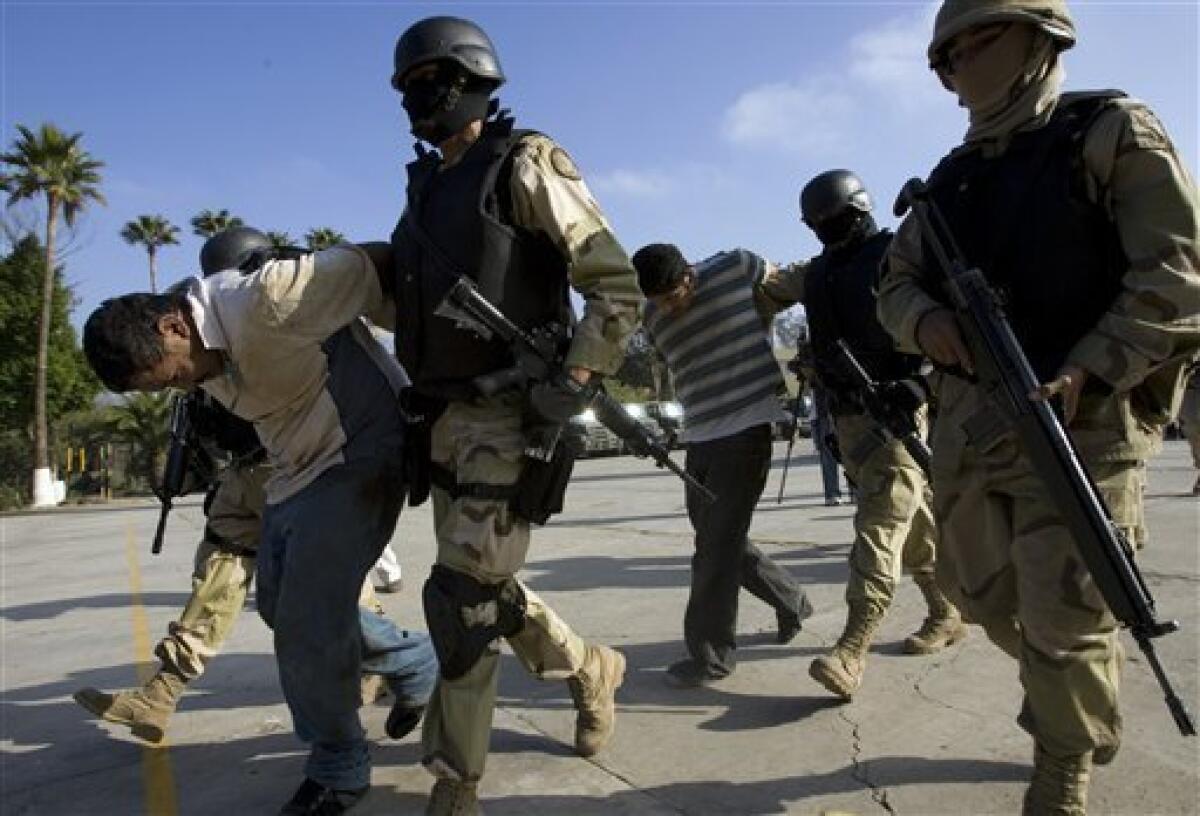 FILE - This Dec. 3, 2008 file photo shows Mexican Army soldiers holding two suspects, arrested during an operation against drug smuggling and kidnapping gangs, after being presented to the press in Tijuana, Mexico. (AP Photo/Guillermo Arias, File)