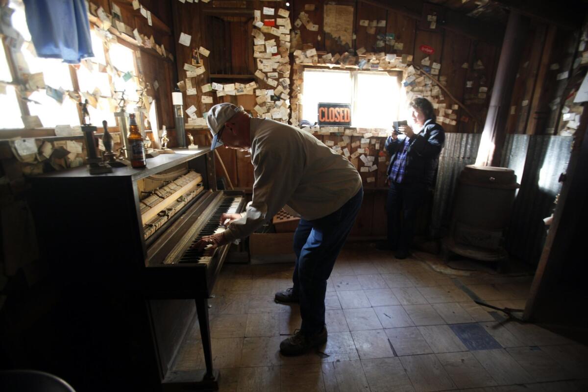 Garn Pringle, left, briefly plays the piano as Jan Goodman takes photos inside the Gin Mill Bar in Seneca, Calif.