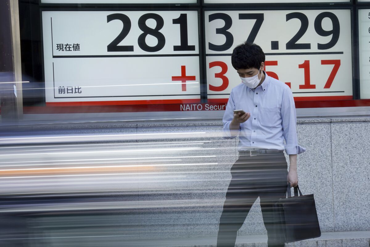 A man wearing a protective mask stands in front of an electronic stock board showing Japan's Nikkei 225 index at a securities firm Wednesday, Oct. 6, 2021, in Tokyo. Asian shares slipped in cautious trading Wednesday, shrugging off a rally on Wall Street, with Tokyo's Nikkei 225 index falling back after opening higher. (AP Photo/Eugene Hoshiko)