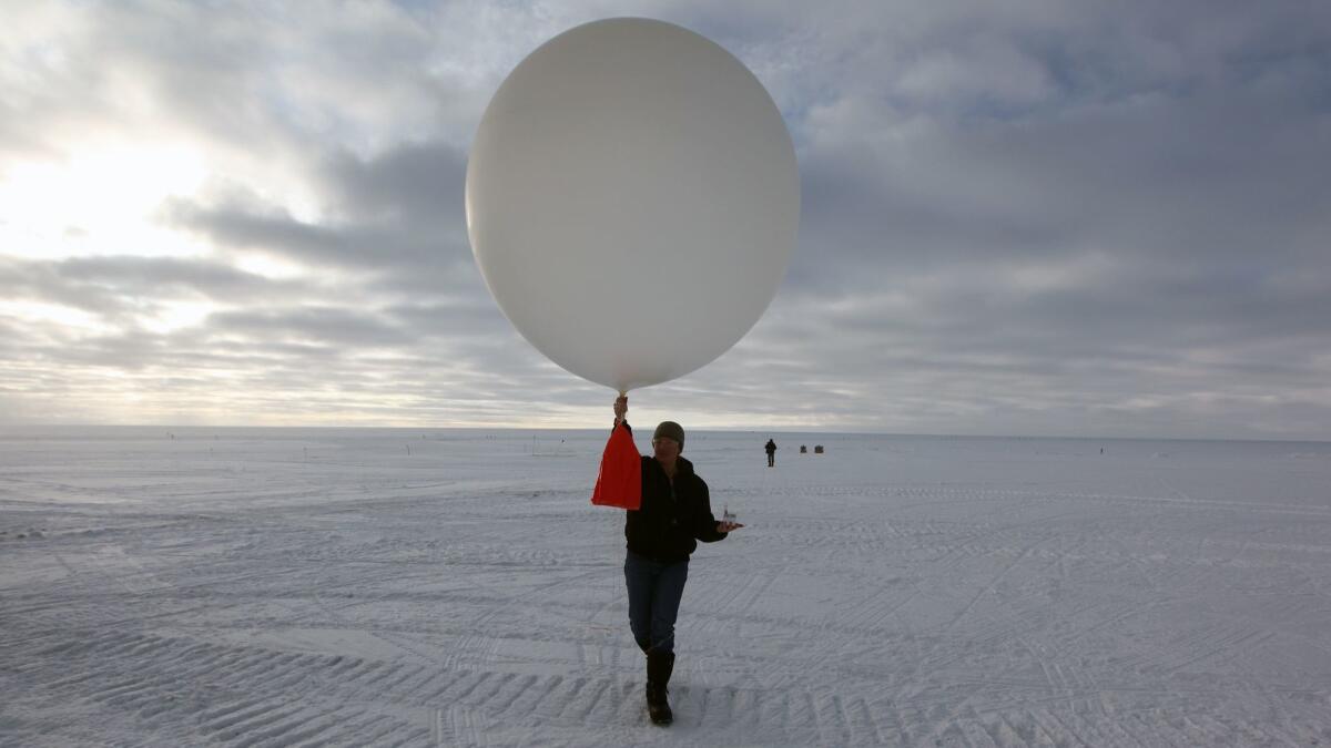 A scientist launches a data-transmitting weather balloon at Summit Station, a remote research site operated by the U.S. National Science Foundation on top of the Greenland ice sheet.