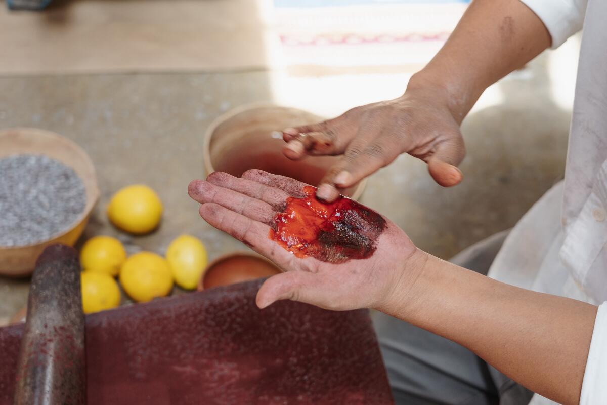 A man rubs cochineal on his hand.