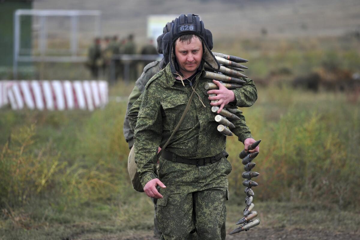 Two Russian recruits walk with a load of ammunition